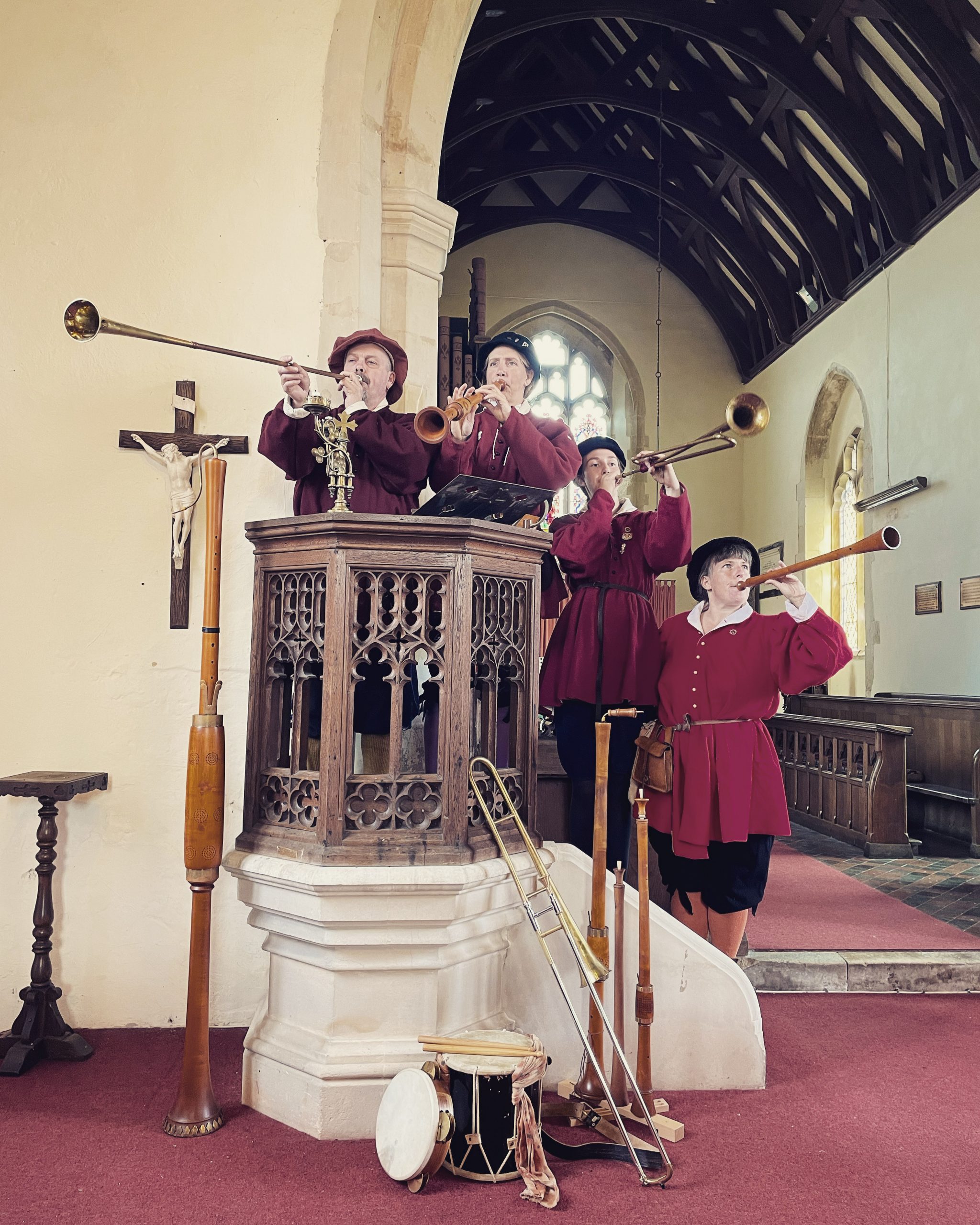 4 historical musicians playing their renaissance instruments from a pulpit