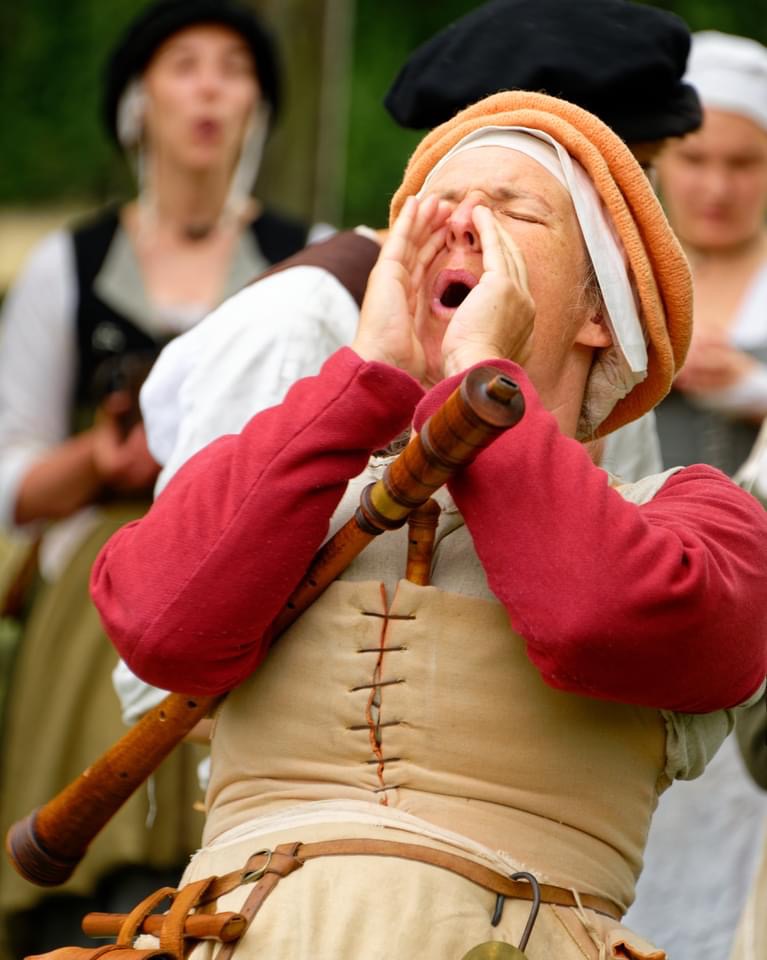 Emma dressed in historical clothing with her hands cupped to her face shouting