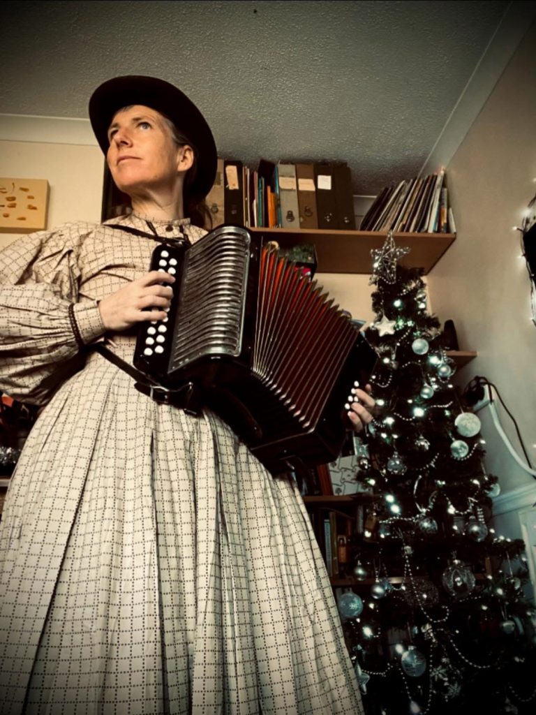 Emma playing the melodeon dressed in Victorian clothing